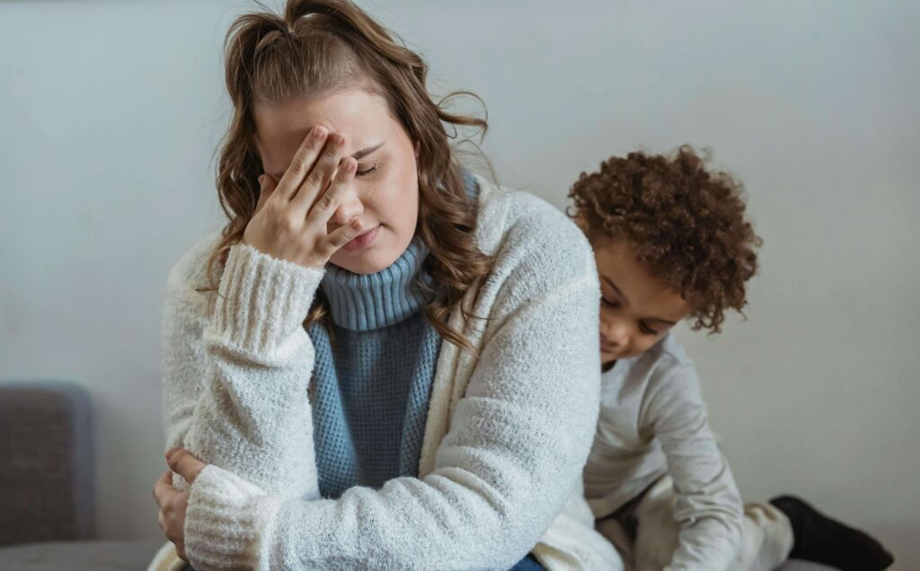 An overwhelmed mother with a child behind her.